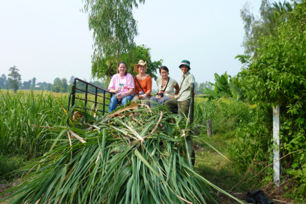 Volunteers on the truck 2 1 A group of individuals seated together on a cart filled with grass