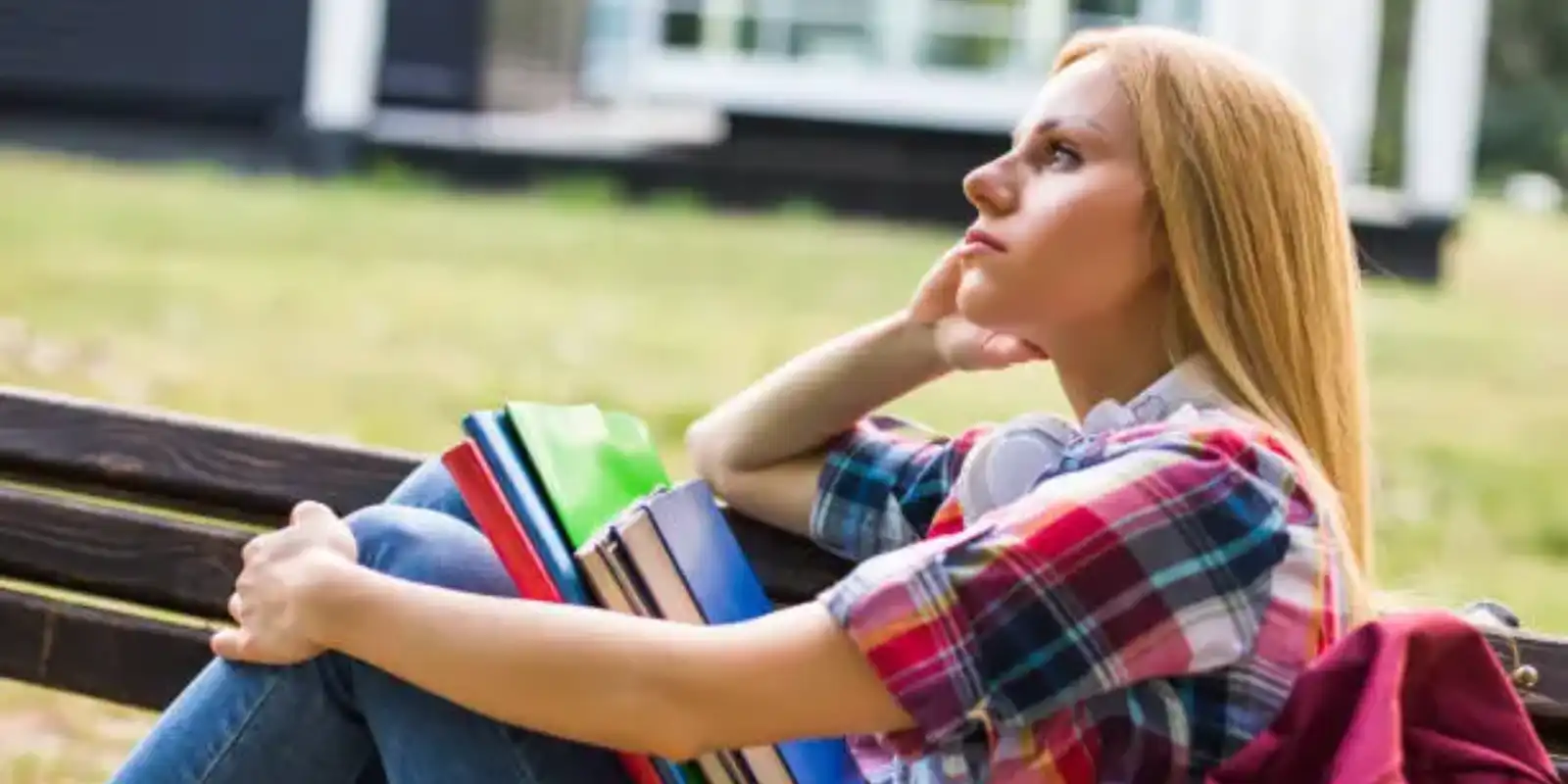 Tired and sad female student studying while sitting outdoor.