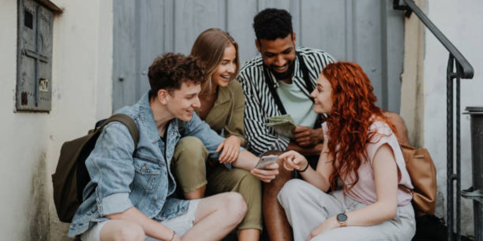 Portrait of group of young people outdoors on trip in town, using map.