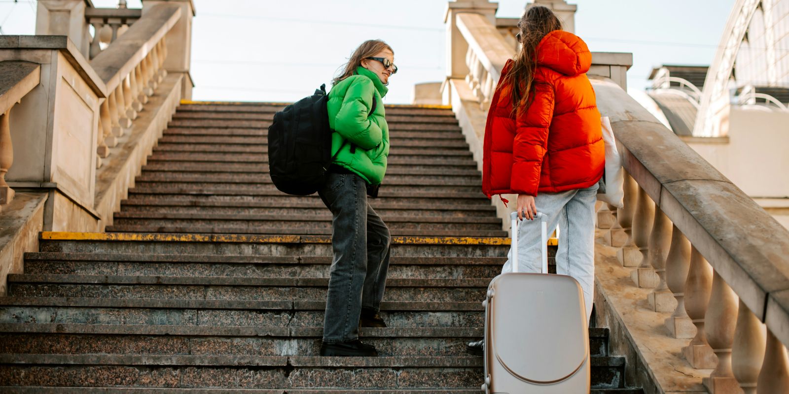 two people walking up a flight of stairs with luggage