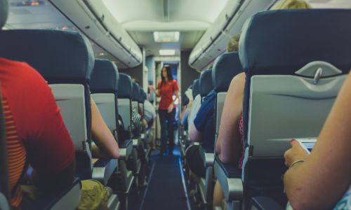 Flight attendant standing between passenger seat