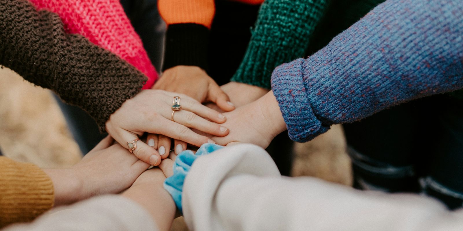 Gap year travelers placing their hands at the center, displaying teamwork.