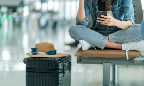 Traveler sitting cross-legged at an airport.